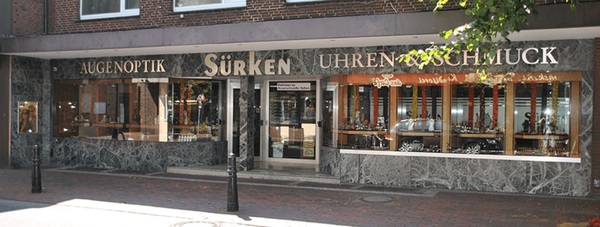 Fassade eines Optiker- und Juweliergeschäfts mit Schaufenstern für Brillen und Schmuck.