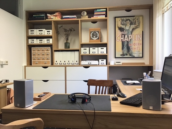 Modernes Homeoffice mit Schreibtisch, Regalen, Computer, Lautsprechern und Deko.